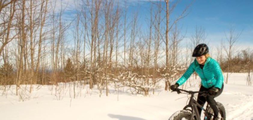 Eine junge Frau fährt mit einem Mountainbike durch die Schneelandschaft