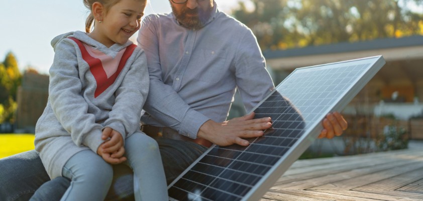 Vater zeigt seiner kleinen Tochter ein Solarpaneel für eine Photovoltaik-Anlage