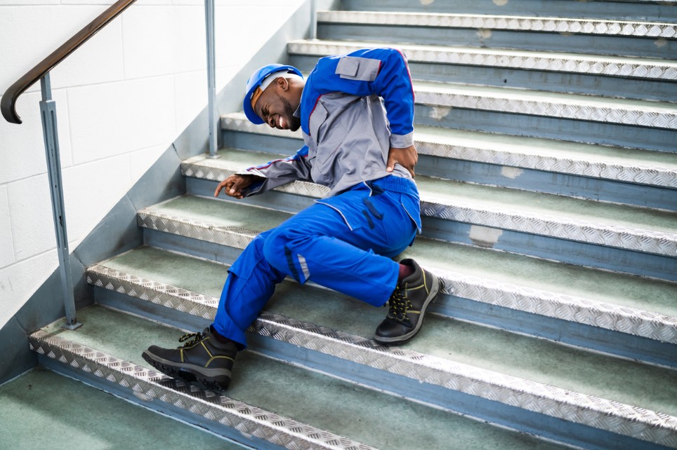 Mann in Arbeitskleidung stürzt auf Treppe