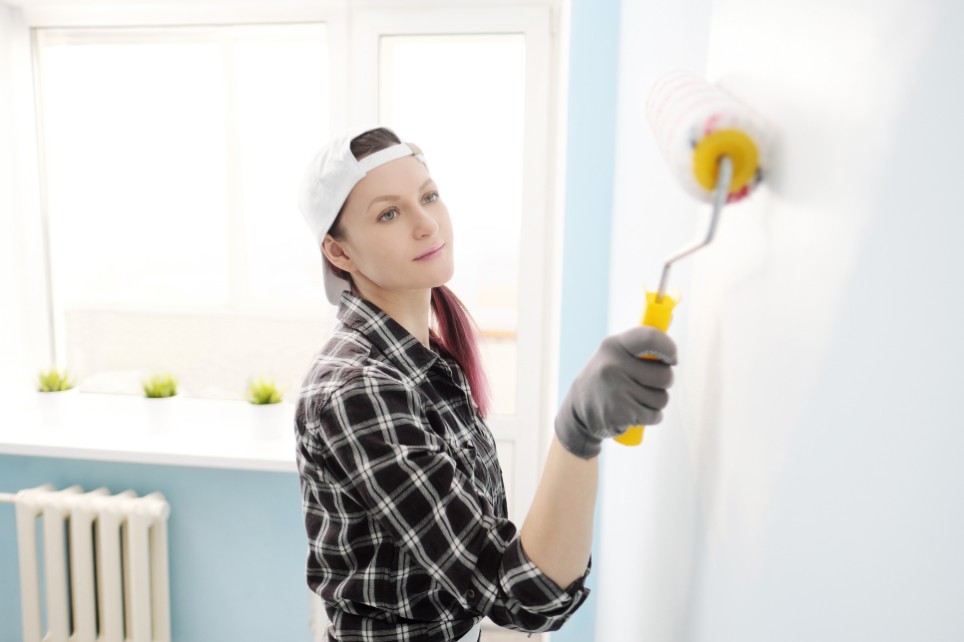 Eine Malerin malt eine Wand an.