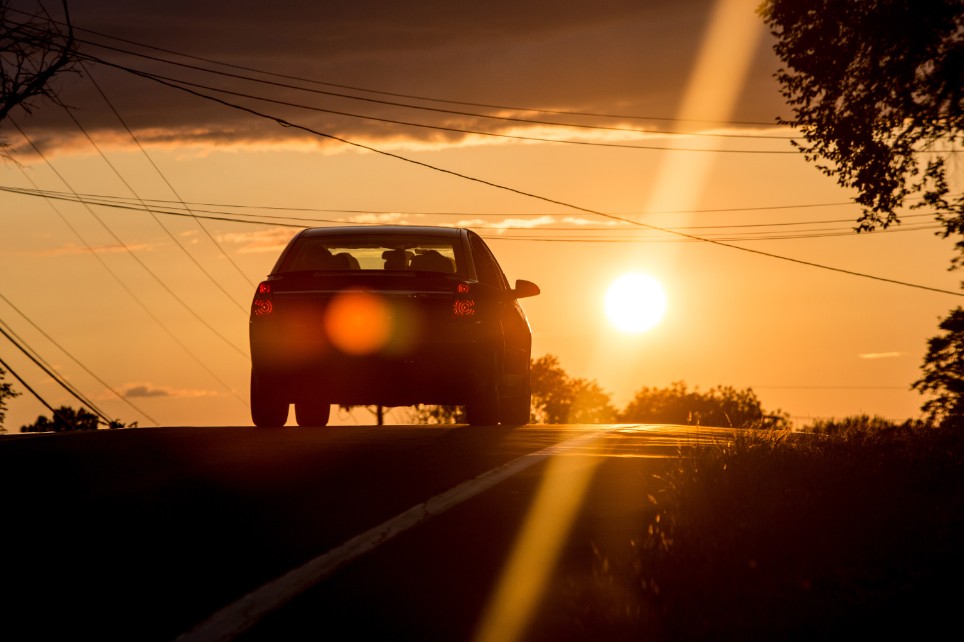 Ein Auto fährt durch die Landschaft der Sonne entgegen Ein Auto fährt durch die Landschaft der Sonne entgegen