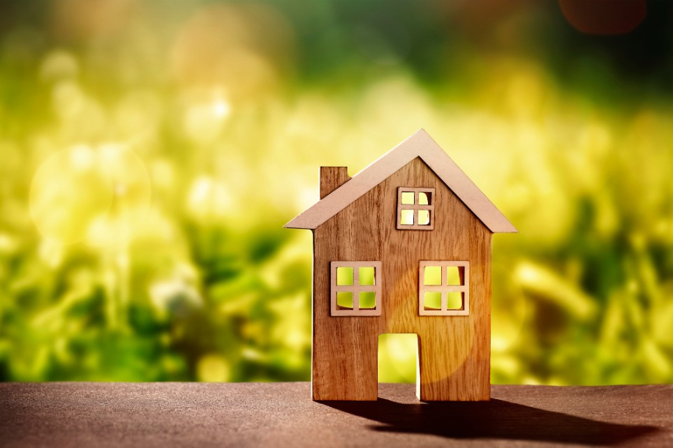 Ein dekoratives kleines Holzhaus stehend auf einem Holzbalken in der Natur Ein dekoratives kleines Holzhaus stehend auf einem Holzbalken in der Natur
