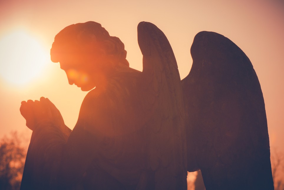 Bühnenbild Ratgeber Trauerfall Im Sonnenuntergang steht eine Engelsstatue.