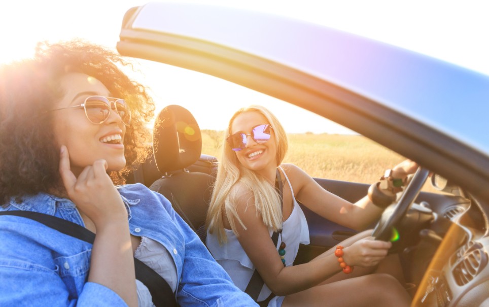 Zwei junge Frauen fahren zusammen im Cabrio in der Sonne Zwei junge Frauen fahren zusammen im Cabrio in der Sonne