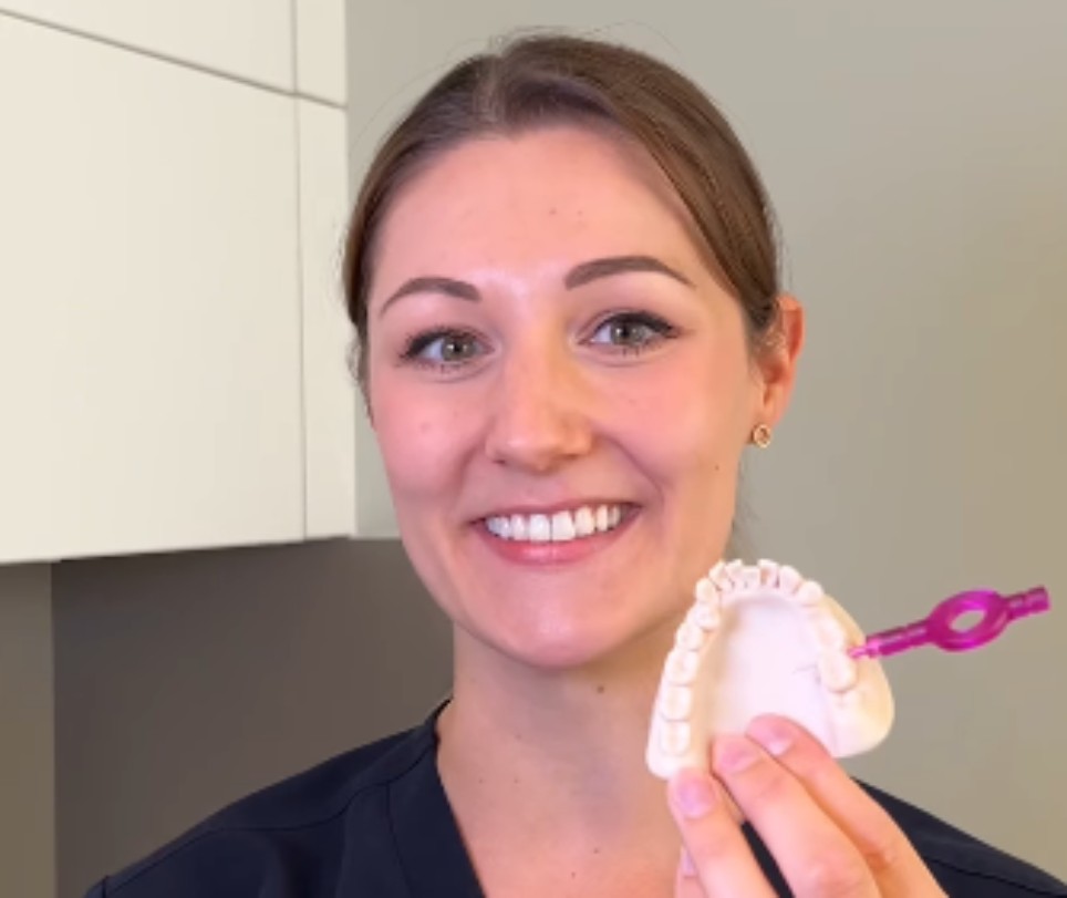 Instagram-Videos Dentalhygiene Eine junge Dentalhygienikerin hält den Abdruck eines Kiefers, in dem eine Interdentalbürste steckt, in der Hand.