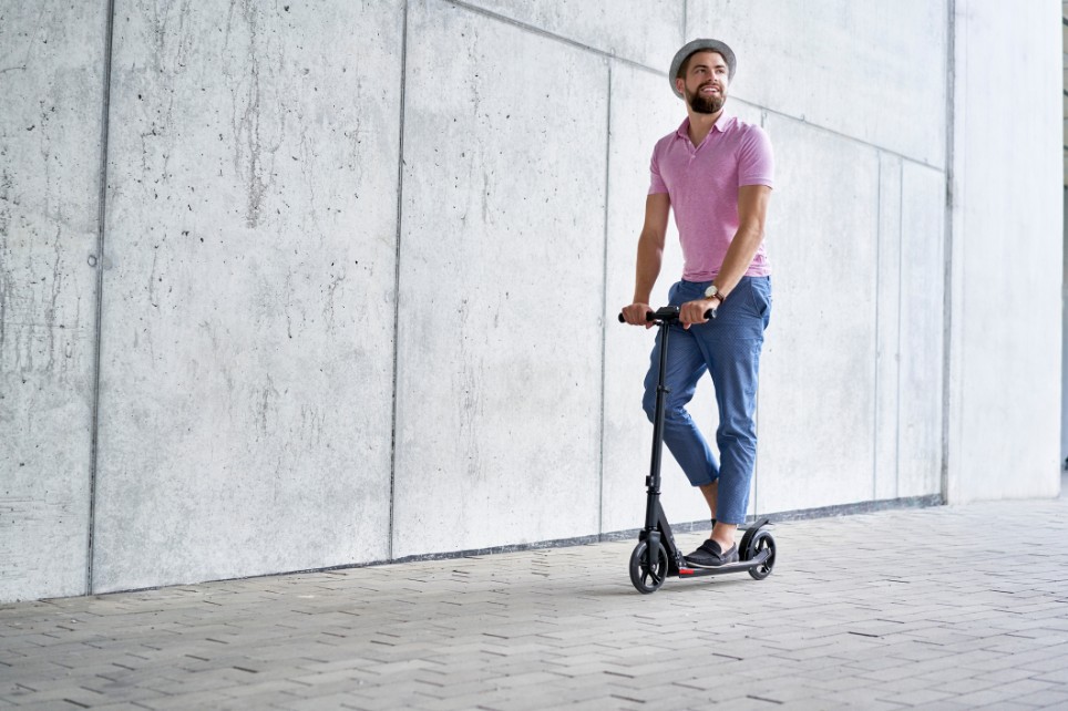 Ein junger Mann fährt mit seinem E-Scooter herum Ein junger Mann fährt mit seinem E-Scooter herum
