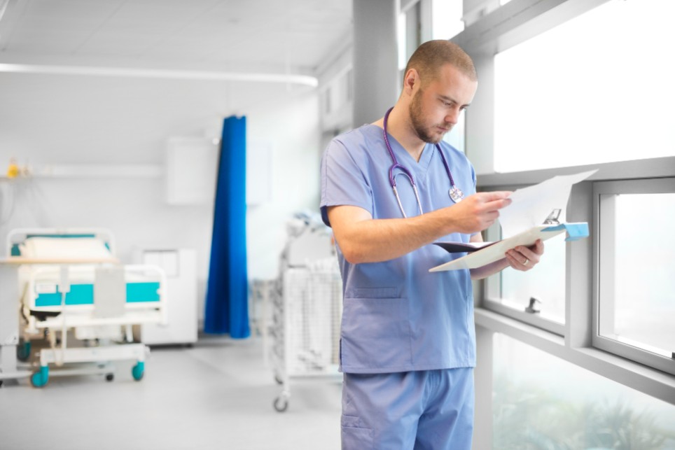 Ein Krankenpfleger liest in einer Patientenakte