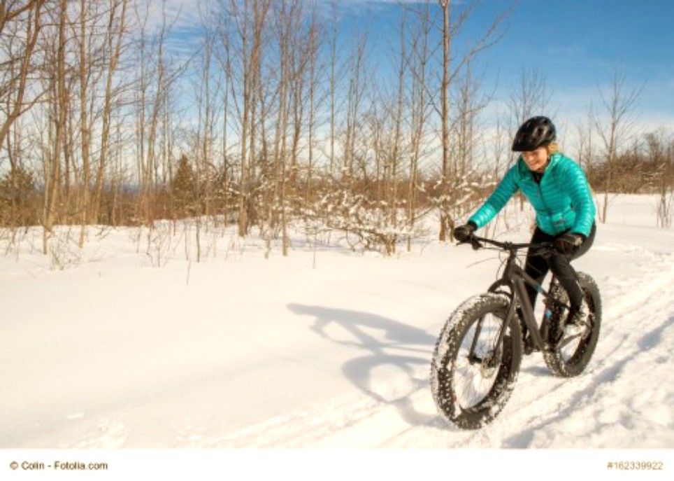 Eine junge Frau fährt mit einem Mountainbike durch die Schneelandschaft