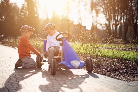 Zwei junge Kinder prüfen gemeinsam den Reifendruck ihres Gokarts