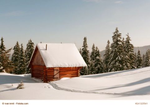 Eine mit mit Schnee bedeckte Holzhütte steht zwischen Tannen in einer Schneelandschaft 