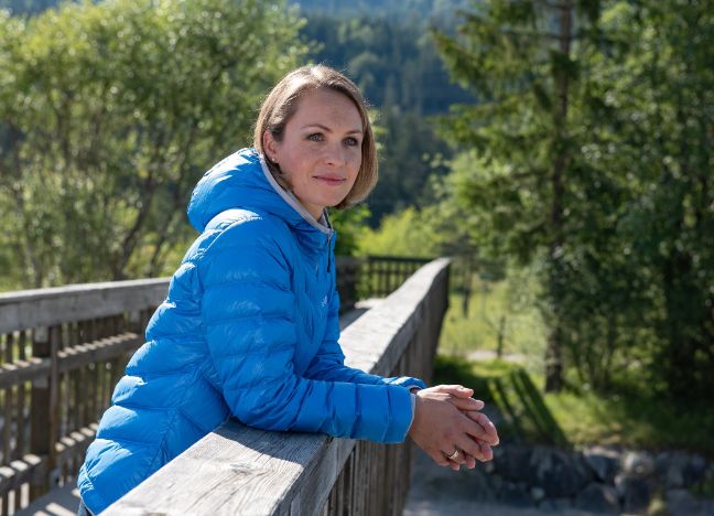 Magdalena Neuer steht auf einer Holzbrücke im Grünen und schaut in die Ferne.